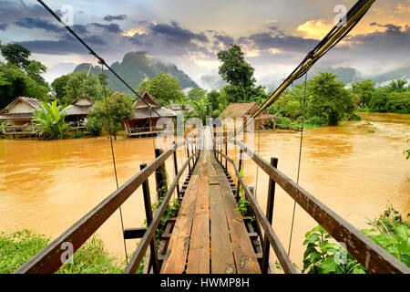 Vang Vieng Laos Wahrzeichen Hüttendorf mit die hölzerne Brücke in trübe und morgen niedrige Lighthing Stockfoto