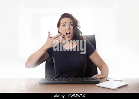 am Schreibtisch sucht Geschäftsfrau gelangweilt im Büro Stockfoto