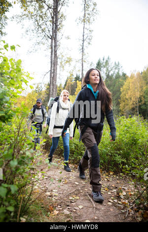 Weibliche Wanderer mit Freunden zu Fuß auf Waldweg Stockfoto