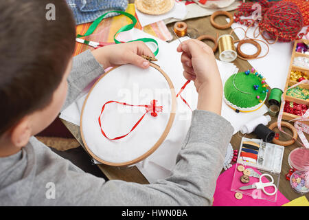 Junge auf Reifen, Hand Closeup und rotes Band auf weißen Textilien bestickt erfährt, Nähen, job, Ausbildung, Handarbeit und Kunsthandwerk-Konzept Stockfoto