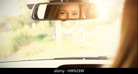 Junge Frau in dem Fahrersitz Blick in den Spiegel in ihrem Auto Stockfoto