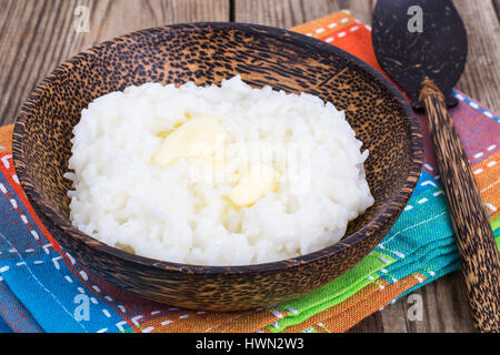 Milch-Reisbrei mit Butter in Holzschale Stockfoto