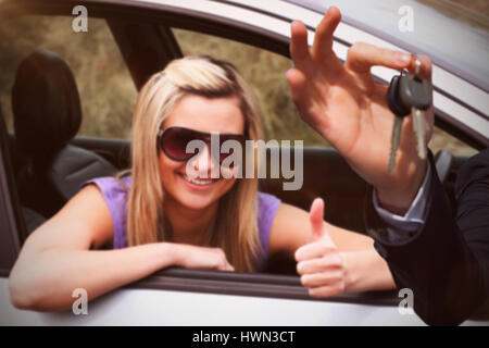 Glückliche Verkäufer Autoschlüssel an glückliche Fahrerin Sonnenbrille mit Daumen oben halten Stockfoto
