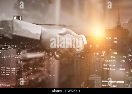 Beleuchtete Gebäude Stadt gegen Himmel gegen Handshake Kollegen Stockfoto