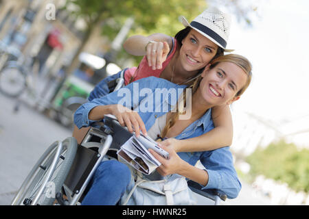 zwei Freunde besuchen, fremde Stadt ein sitzen im Rollstuhl Stockfoto