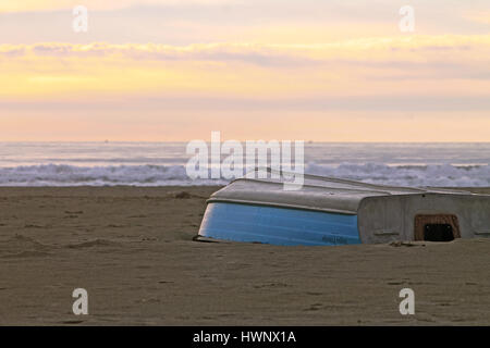 Ruderboot auf dem Kopf stehend an einem Strand bei Sonnenuntergang Stockfoto