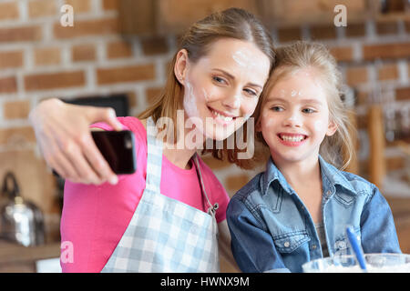 Porträt des Lächelns, Mutter und Tochter machen Selfie beim Kochen zu Hause Stockfoto