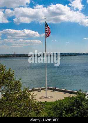 Blick vom Ellis Island in der Upper New York Bay mit amerikanische Flagge im Vordergrund und Governors Island und Brooklyn im Hintergrund Stockfoto