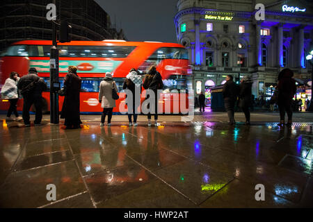 Londoner Routemaster Bus in Piccadilly Circus Leute im Regen stehen Stockfoto