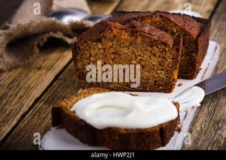 Hausgemachte Kürbis-Brot mit Frischkäse Puderzucker in Scheiben geschnitten und bereit, auf rustikalen Holztisch essen Frühstück Stockfoto