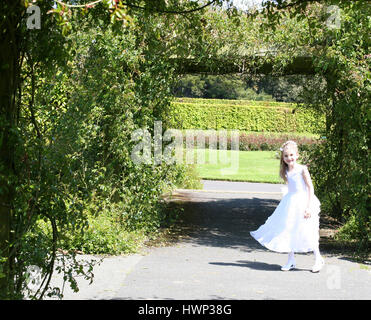 Mädchen am Tag ihrer ersten Heiligen Kommunion im Garten Stockfoto