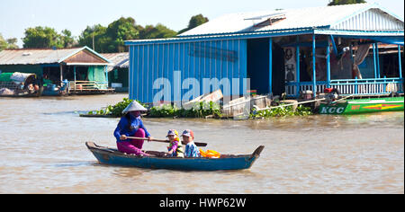 Kambodschanische Frau benutzt Ruder, um ihre Kinder mit dem Boot zur Schule in Kampong Chhnang treiben Stockfoto