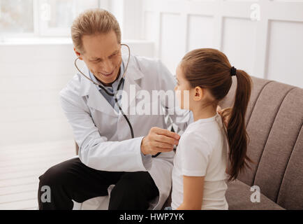 Einmal tief durchatmen. Schön ausgebildete freudige Arzt hören seine kleinen Patienten atmen während machen einige Tests vor dem schreiben, einige Medikamente Stockfoto