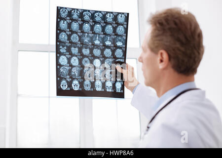 Fokus. Aufmerksame clever ausgewiesener Experte sorgfältig durchsehen MRI Gehirn-Scans, während sie gegen die Witwe und auf der Suche nach th Stockfoto