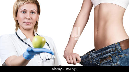 Arzt hält grünen Apfel. Junge Frau zeigt Gewicht-Verlust-Ergebnis. Gesunde Ernährung-Konzept. Stockfoto