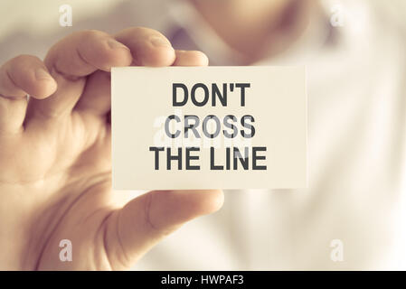 Closeup auf Geschäftsmann hielt eine Karte mit Text DONT CROSS THE LINE, Business Konzept Bild mit soft-Fokus-Hintergrund und Vintage-Ton Stockfoto