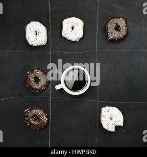 Tic Tac Toe Donuts und Kaffee über Schwarzes Brett Hintergrund. Bild von oben. Stockfoto