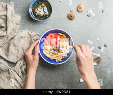 Frauenhand mit Honig drizzlier und blau gesundes Frühstück Schüssel Stockfoto