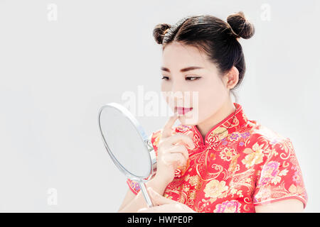 Nahaufnahme der chinesischen Asiatin Check Make-up Gesicht mit Mirrio und Kostüm in Cheongsam China Tradition Kleid in Neujahrsfest auf weißem Hintergrund Stockfoto