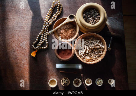 Erhöhte Ansicht von Kräutern in Schalen mit Gebetskette auf Tisch Stockfoto