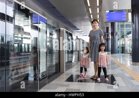 Asiatische chinesische Mutter und Töchter warten auf Transit an der MRT Station in Kuala Lumpur, Malaysia. Stockfoto