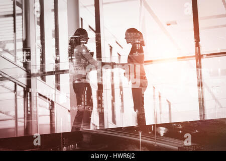 Beleuchteten Gebäuden in der Stadt gegen Geschäftsfrauen handshaking Stockfoto