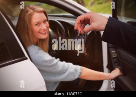 Paar empfangen Autoschlüssel von einem Händler gegen Porträt der jungen Frau im Auto Stockfoto