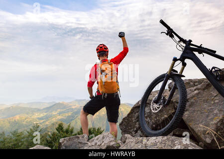 Mountain Biker Erfolg, am Radweg in herbstliche Bergwelt betrachten. Wir feiern schöne inspirierende Landschaft. Erfolgreiche glücklicher Fahrer auf ro Stockfoto