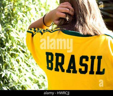 ein junges Mädchen, das Tragen einer Sport-Shirts in die Brasil Nationalfarben grün und gelb mit Brasil dargelegt quer über den Rücken Stockfoto