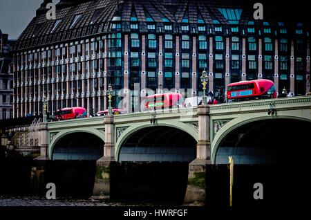 Drei roten Busse überqueren Westminster Brücke, weiter nach dem anderen, als eine Art Schlange, eines der berühmtesten Wahrzeichen Londons Stockfoto