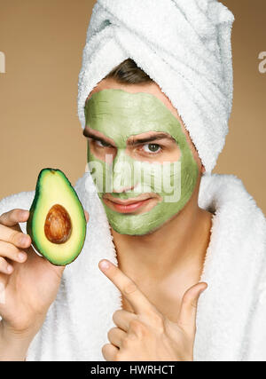 Mann mit Handtuch und Gesichtsmaske von Avocado. Foto von gepflegten Mann Spa-Behandlungen erhalten. Schönheit & Skin care Konzept Stockfoto