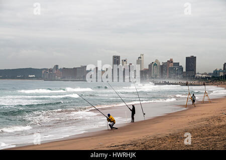 DURBAN, Südafrika - 23. März 2017: drei unbekannte am frühen Morgen Fischer am Strand gegen bewölkten Skyline von Durban in Südafrika Stockfoto