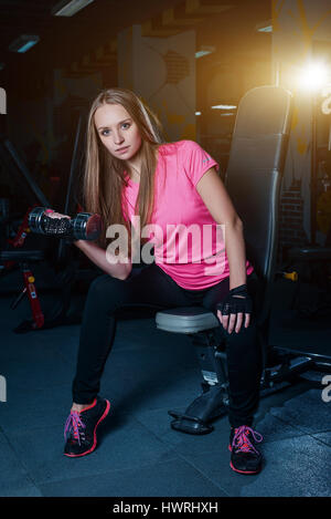 Attraktive sportliche Mädchen tun Training mit Hanteln im Fitnessstudio. Schöne Fitness-Frau arbeitet an ihren Bizeps Stockfoto