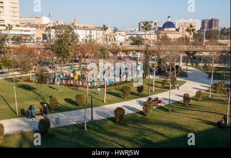 Blick über Jardin del Turia (Turia Gärten) mit Spielplatz und die Stadt im Hintergrund. Valencia, Spanien. Stockfoto