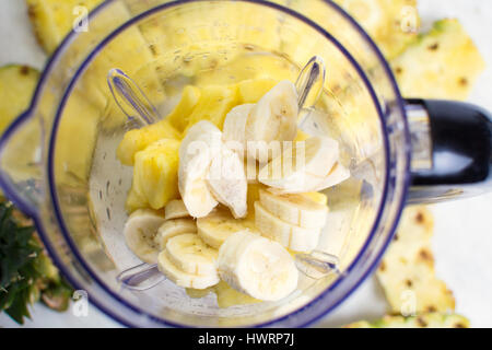 In Scheiben geschnittene Ananas und Banane in einen Mixer geben Stockfoto