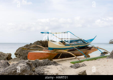 Zwei abgesteckt philippinischen Fischer Pumpe Boote bis auf den Strand, geschützt durch die Felsen an einem weißen Sandstrand. Stockfoto