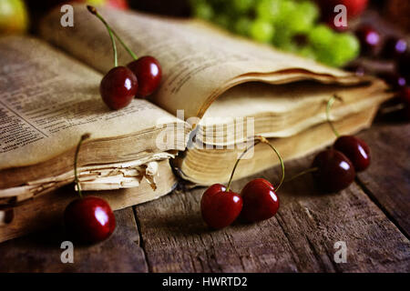 Retro-Buch auf hölzernen Hintergrund und Cherry berry Stockfoto