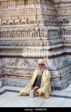 Sadhu sitzt mit gekreuzten Beinen durch eine typische geschnitzte Wand in der Jagdish-Tempel, ein Hindu-Tempel in Udaipur, indischen Bundesstaat Rajasthan, Indien Stockfoto