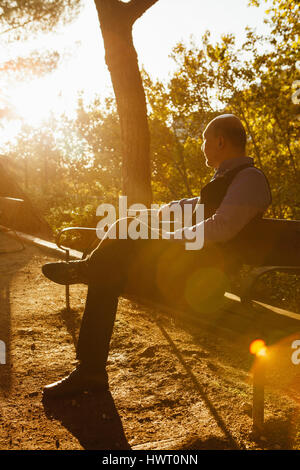 Nachdenklicher Mann auf Bank im Park sitzen Stockfoto
