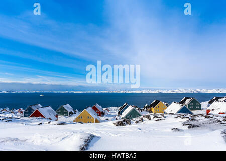 Gelbe, blaue, rote und grüne Inuit Häuser schneebedeckt am Fjord der Stadt Nuuk, Grönland Stockfoto