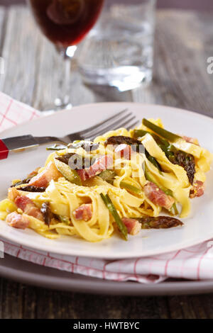 Italienische Pasta Carbonara mit Spargel. Auf rustikalem Holztisch. Stockfoto