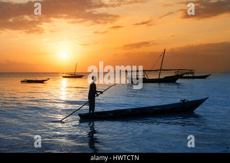 Mann auf einem traditionellen Boot vor der Küste Sansibars bei Sonnenuntergang. Reisen, Urlaub, Abenteuer, Tourismus-Konzept. Stockfoto