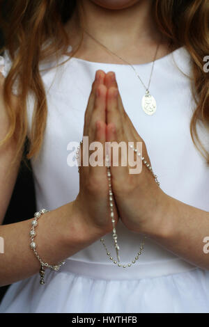 Kommunion Mädchen mit Händen drapiert in Silber Rosenkranz Stockfoto