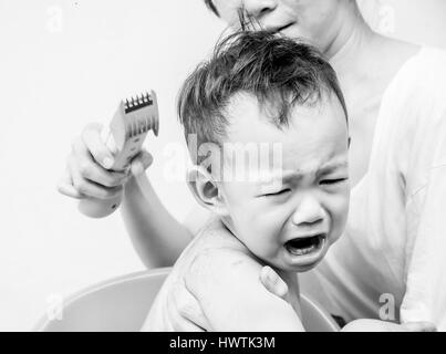 Angst, Thai baby fühlen Angst der Haarschneider als Mutter seine Haare schneiden Stockfoto