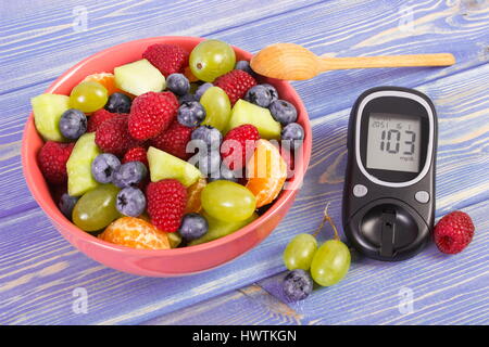 Frisches Obst Salat und Glucose Messgerät mit Ergebnis der Messung Blutzuckerspiegel, Konzept von Diabetes, Diät, abnehmen, gesunde Lebensweise und Ernährung Stockfoto