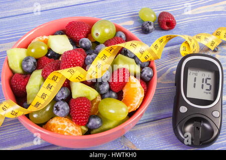 Salat von frischen Früchten, Blutzuckermessgerät mit Ergebnis der Messung Zuckergehalt und Maßband, Konzept von Diabetes, Diät, abnehmen, gesunde Lebensweise und Stockfoto