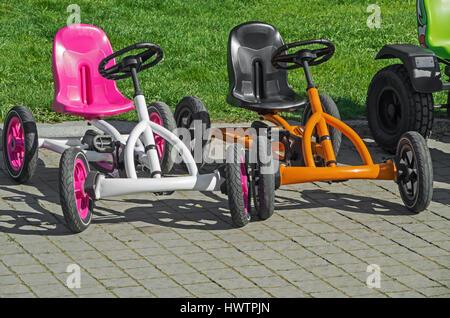 Zwei vierrädrige Kinderfahrräder auf Bürgersteig im Freizeitpark Stockfoto