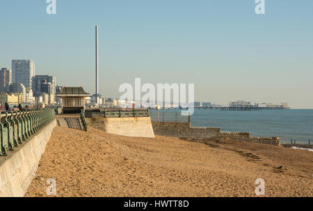 Strand und Meer promenade mit i360 Aussichtsturm und Piers im Hintergrund. East Sussex, England. Mit unkenntlich Menschen. Stockfoto