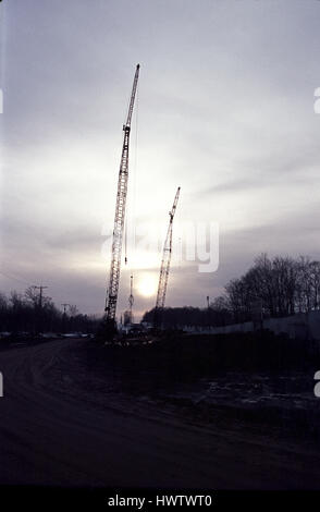 Bau-Krane Silhouette gegen eine Einstellung Sonne Stockfoto