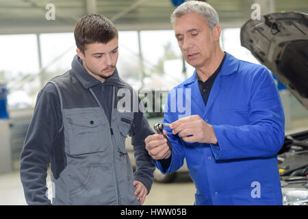 Schüler mit Lehrer, die Reparatur eines Autos während der Lehrzeit Stockfoto